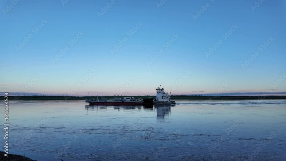 A ferry boat travels across a river at dusk in the Russian Far East. The sky is a beautiful blue and pink, and the water is calm and still. A ferry boat travels across a river at dusk in the Russian Far East. The sky is a beautiful blue and pink, and the water is calm and still.