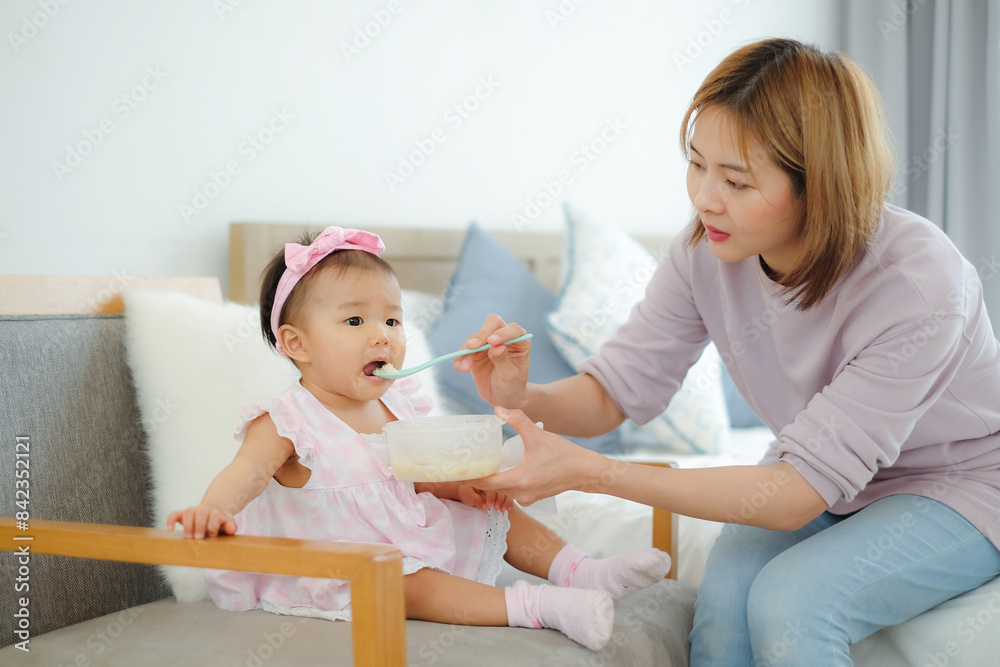 Beautiful young asian mother is feeding her baby soft food for good growth and nutrition. Beautiful young asian mother is feeding her baby soft food for good growth and nutrition.
