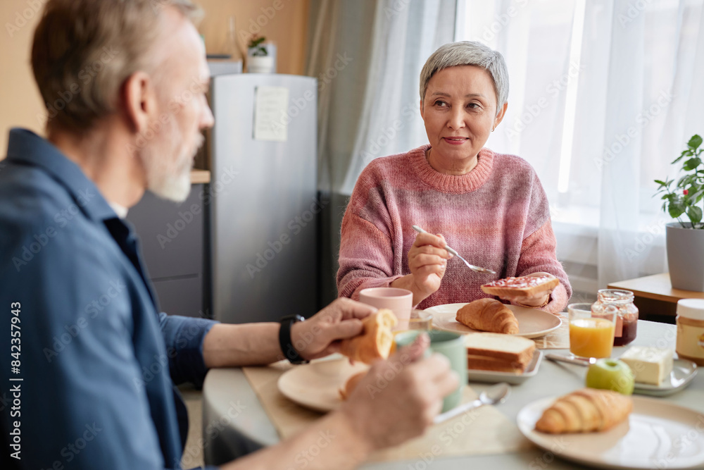 Portrait of Asian senior woman enjoying breakfast at dinner table with husband in cozy kitchen Portrait of Asian senior woman enjoying breakfast at dinner table with husband in cozy kitchen
