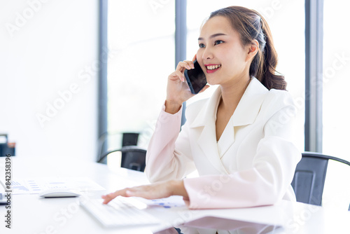 Asian Businesswoman Using laptop computer and working at office with calculator document on desk, doing planning analyzing the financial report, business plan investment, finance analysis concept. 