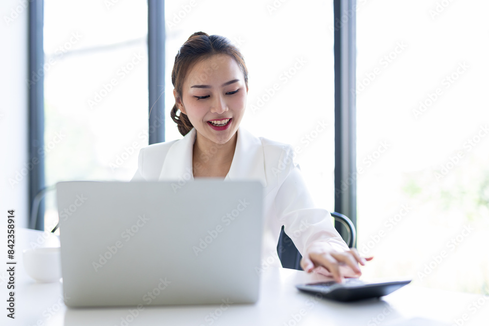 Asian Businesswoman Using laptop computer and working at office with calculator document on desk, doing planning analyzing the financial report, business plan investment, finance analysis concept.
Asian Businesswoman Using laptop computer and working at office with calculator document on desk, doing planning analyzing the financial report, business plan investment, finance analysis concept.