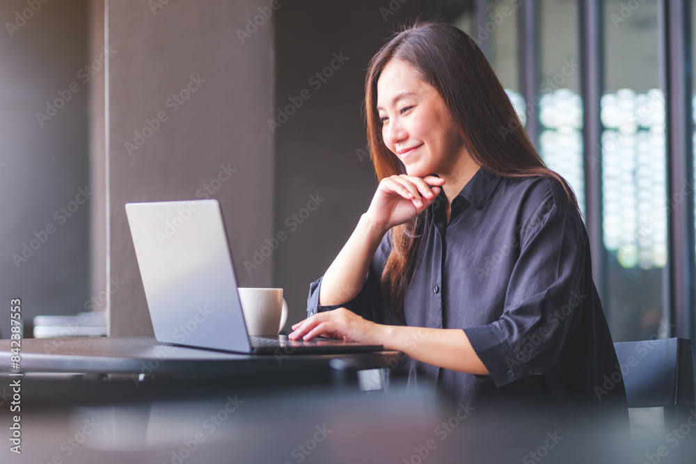 Portrait image of a young woman working on laptop computer in cafe Portrait image of a young woman working on laptop computer in cafe