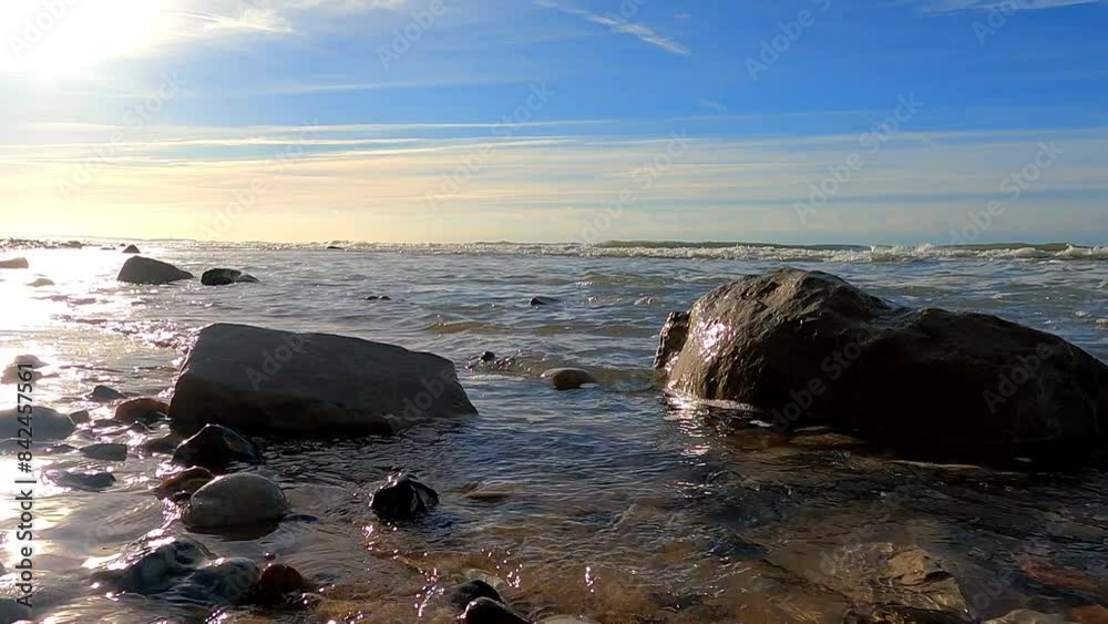 The tranquil scene of calm waves washing against a rocky shore under a clear blue sky showcases the beauty of the coast The tranquil scene of calm waves washing against a rocky shore under a clear blue sky showcases the beauty of the coast