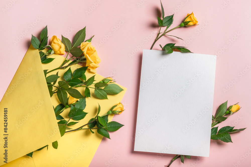 Invitation or greeting card mockup with yellow envelope, blank card with small yellow roses on pink background. Copy space. Invitation or greeting card mockup with yellow envelope, blank card with small yellow roses on pink background. Copy space.