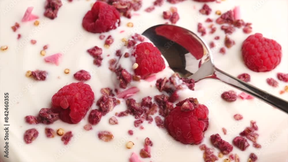 yogurt with raspberry and Pink Granola, rotation in circle. Greek natural yogurt with red berry, Turning. Scoop yogurt with pink chocolate pieces with a spoon yogurt with raspberry and Pink Granola, rotation in circle. Greek natural yogurt with red berry, Turning. Scoop yogurt with pink chocolate pieces with a spoon