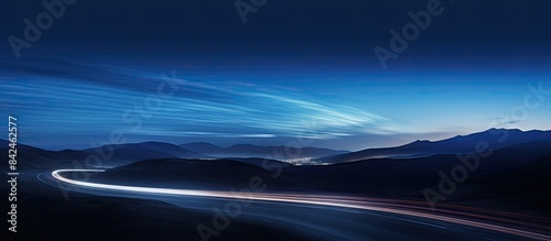 Vehicles leaving light trails on a road under moonlight with space for additional images.