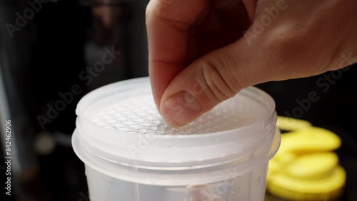 Close-Up of a Sports Shaker Cup for Mixing Powder Supplements for Workouts, with a Mesh Insert and Yellow Lid. photo