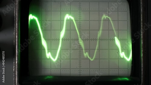 A vintage oscilloscope displays a dynamic green waveform, showcasing the beauty and precision of analog signal visualization. photo