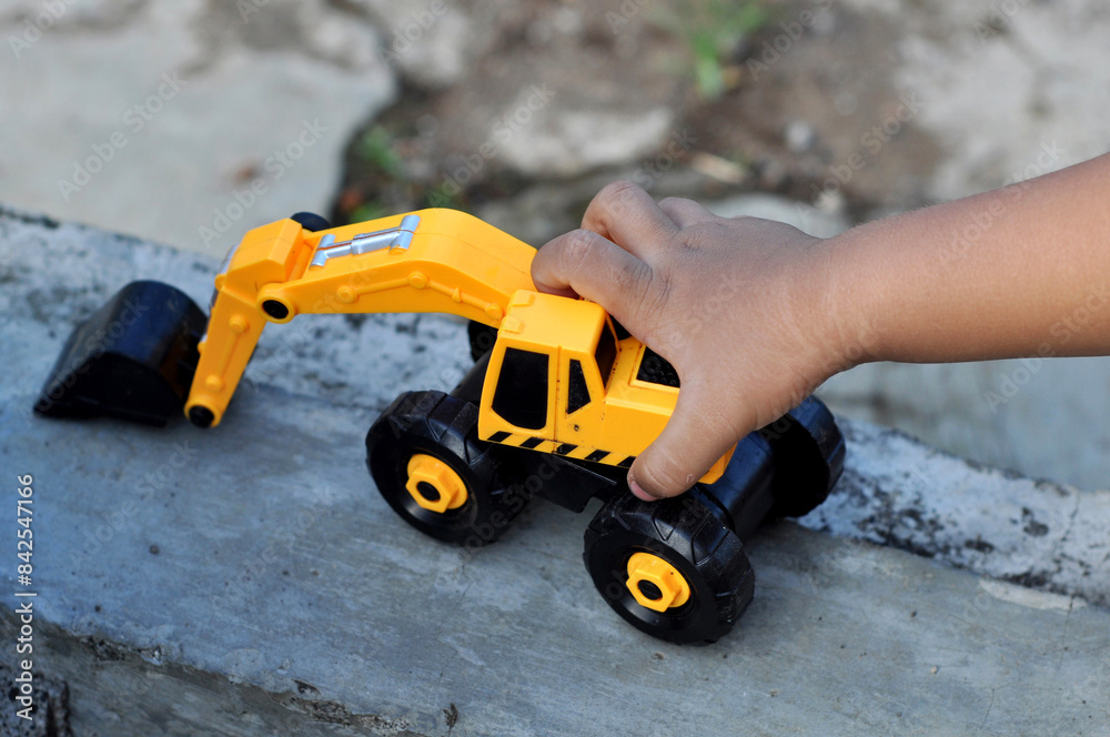 Children holding yellow excavator vehicle toy outdoor