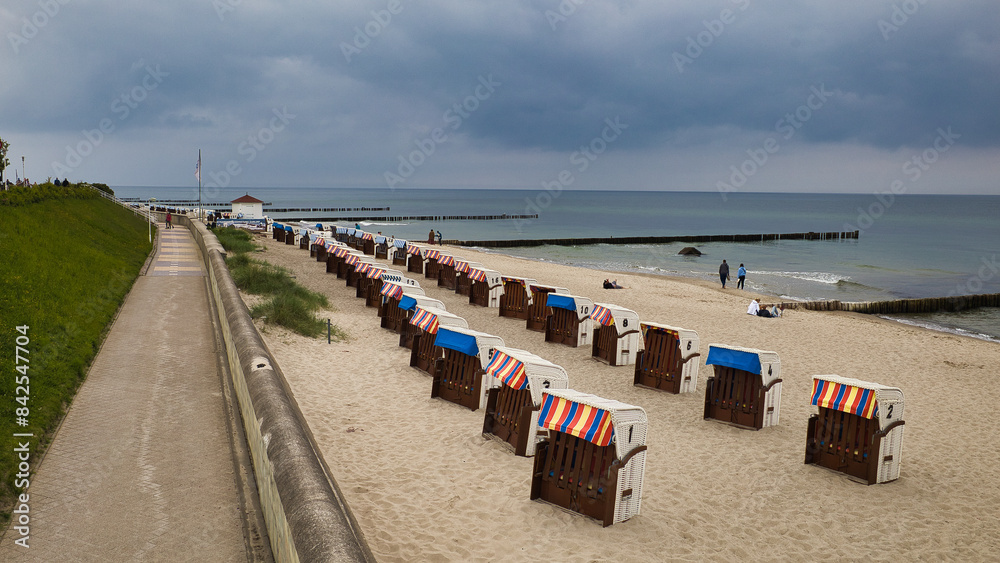 Obraz premium Blick von der Strandpromenade auf ordentlich aufgereihte Strandkörbe am Ostseestrand von Kühlungsborn bei bewölktem Himmel, Mecklenburg-Vorpommern, Deutschland