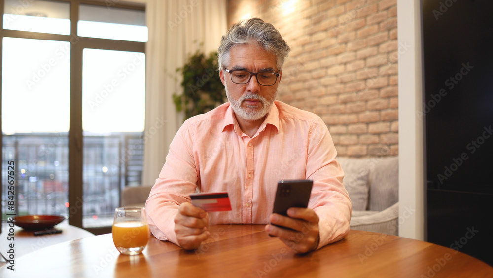 Mature man using smartphone and shopping online at home Mature man using smartphone and shopping online at home