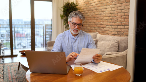 Bild auf Leinwand Mature man managing his finances at home