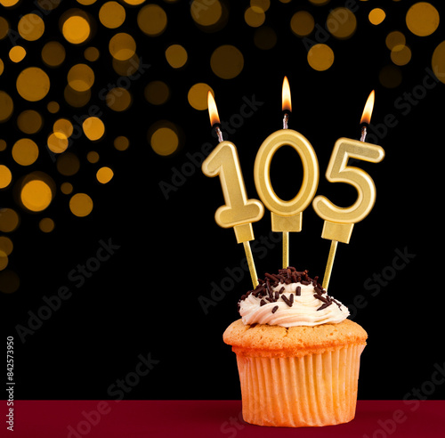 Birthday candle with cupcake - Number 105 on black background with out of focus lights photo