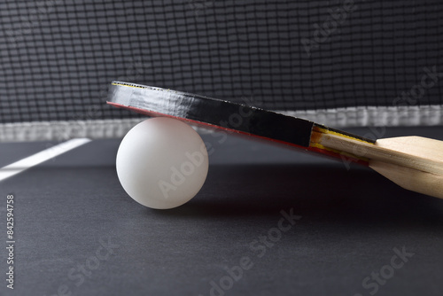 Ping-pong paddle resting on white ball on black game table