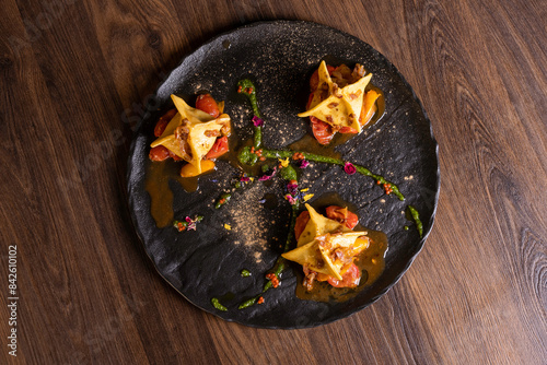 Fagottino di pasta fresca ripieno di funghi porcini con salsa ai 3 pomodori e guanciale croccante servito come primo piatto in un ristorante photo