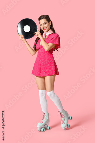 Portrait of beautiful pin-up woman in roller skates with vinyl disk on pink background © Pixel-Shot