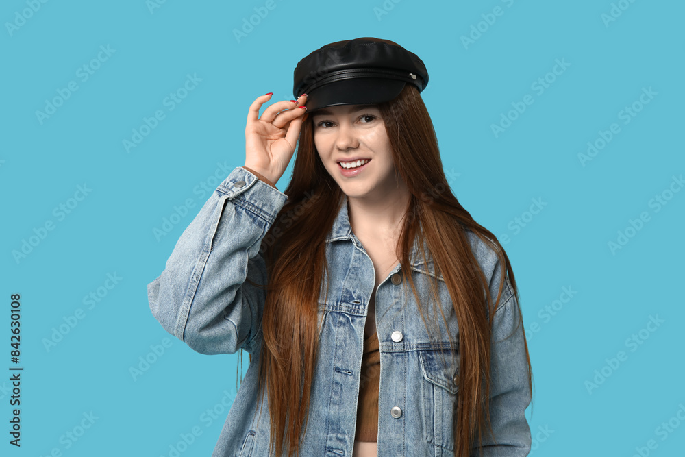 Stylish young girl in hat and jeans jacket on blue background Stylish young girl in hat and jeans jacket on blue background