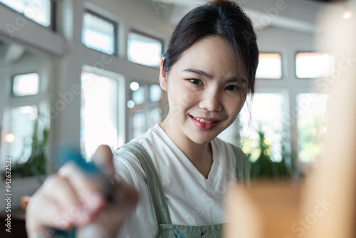 Young Woman Enjoying Creative Hobby Indoors - Smiling Female Engaged in Artistic Activity at Home - Bright and Airy Room with Natural Light - Focus on Leisure and Personal Development