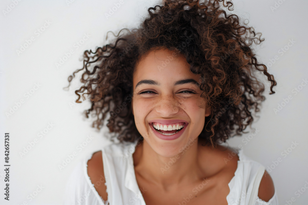 a woman with curly hair smiling and looking at the camera a woman with curly hair smiling and looking at the camera