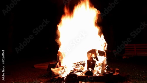 Bonfire Blaze. A mesmerizing slow-motion shot of a couch ablaze in a backyard fire pit, flames dancing against the night sky.