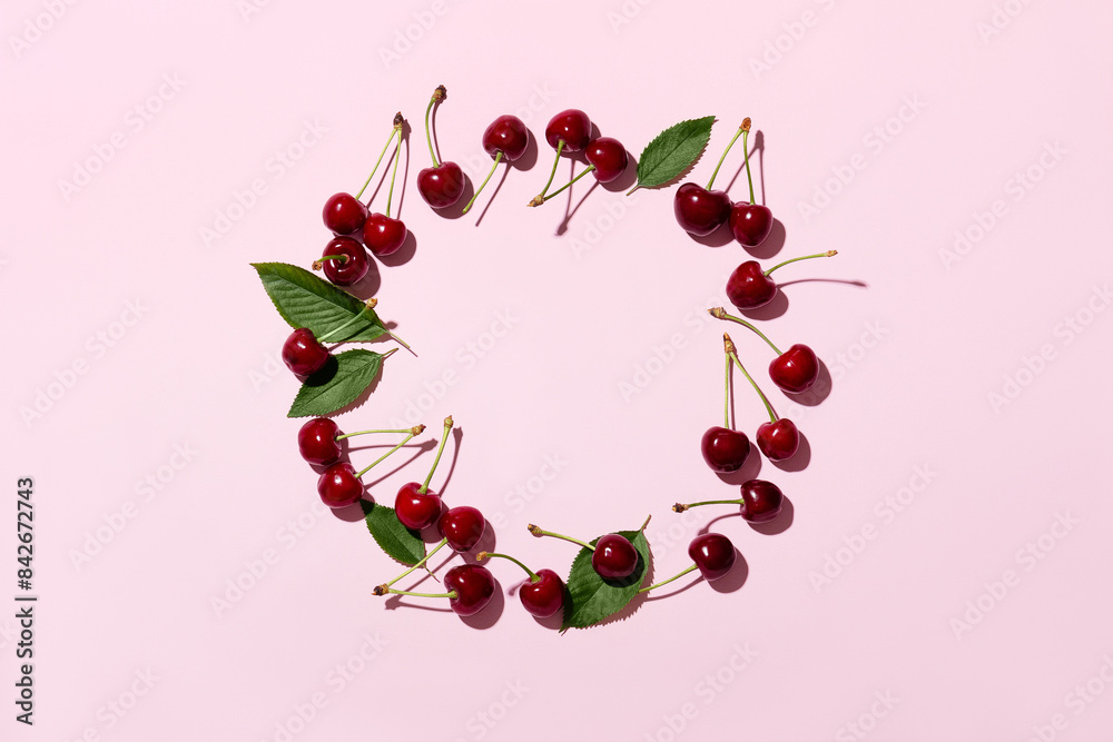 Round pink frame and ripe cherries on a pink background. Cherries or sweet cherries on a pink background. Top view. Space for text. Round pink frame and ripe cherries on a pink background. Cherries or sweet cherries on a pink background. Top view. Space for text.