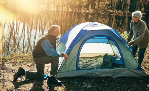 Old couple  tent and camping with nature  help and vacation with hobby  retirement and conversation. Outdoor  senior man or mature woman with sunshine  mountains or holiday with getaway trip or relax