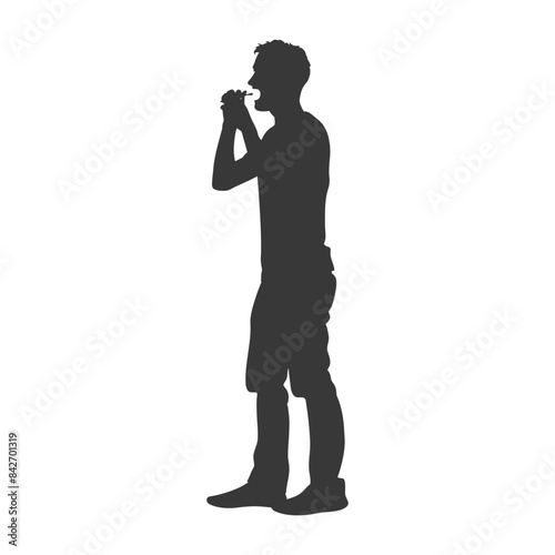 Silhouette of Man Standing and Eating a Burger.