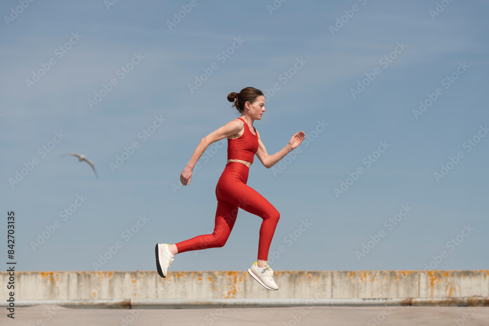 mid adult woman running and jogging outside, blue sky background mid adult woman running and jogging outside, blue sky background