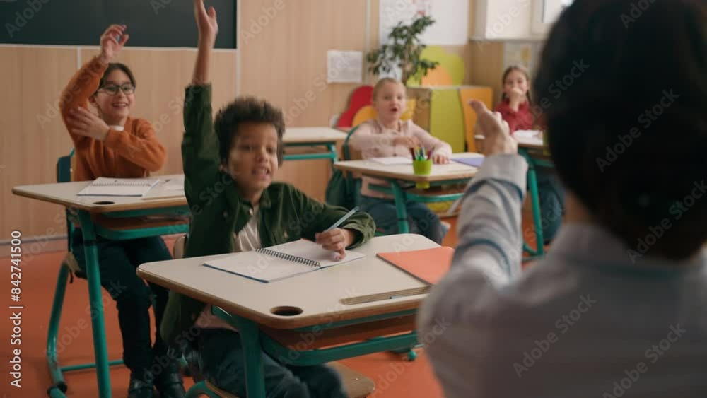 School class lesson group of multiracial diversity multiethnic children kids studying learning rise hands unrecognizable woman teacher back view choose girl answer tutor talking study learn education
