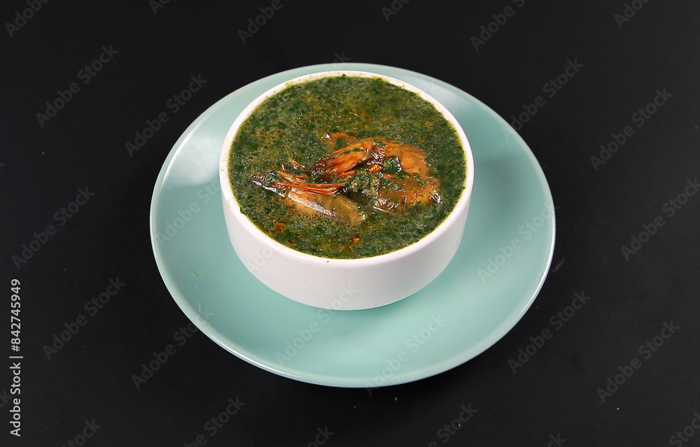 Famous traditional Arabic cuisine. Molokhia green soup with shrimps on black background. Flat lay, top view. Moroheiya Famous traditional Arabic cuisine. Molokhia green soup with shrimps on black background. Flat lay, top view. Moroheiya