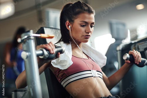 Girl, workout and chest press in gym for fitness, power and muscle development with commitment or towel. Training, athlete and exercise in sports club for health, wellness or results with earphones © peopleimages.com
