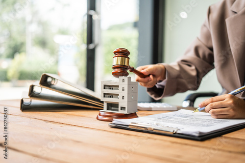 A young businesswoman is working at her desk, managing lease agreements and coordinating with the HOA for an apartment complex, focusing on tenant relations and property maintenance.
