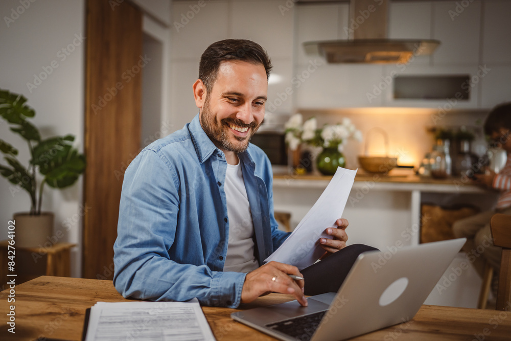 Fototapeta premium man work form home hold document use laptop with son at background