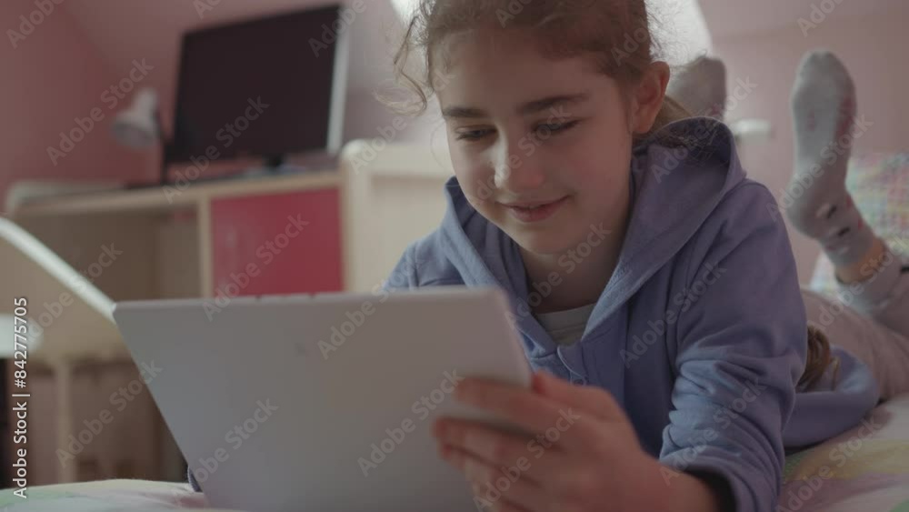 Child Using Digital Tablet Browsing Internet Chat At Home. Girl Watching Online Video Social Media on Digital Tablet in Bed in Bedroom. Dependence on Social Networks in Children. Not Healthy Lifestyle