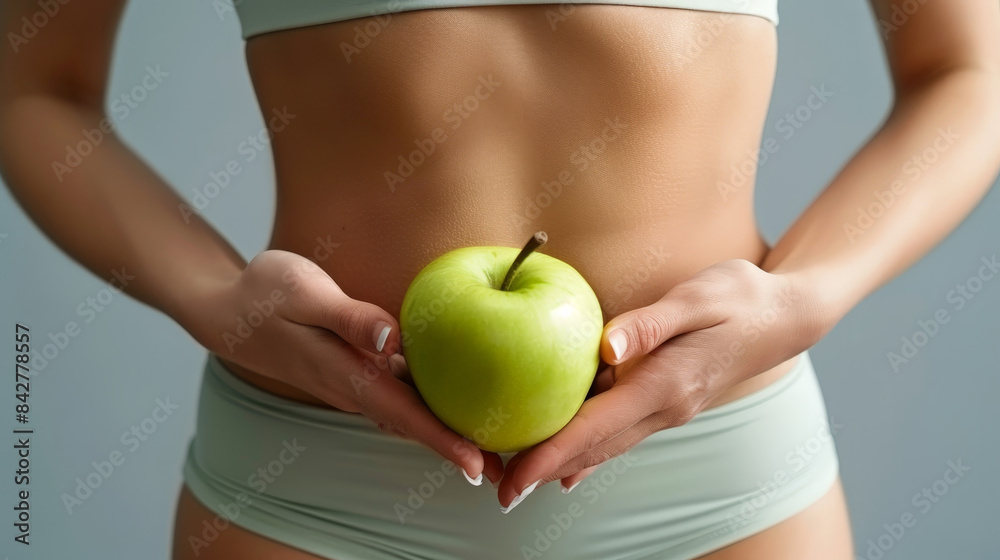 A woman holding an apple while showcasing her toned stomach, chest, and waist A woman holding an apple while showcasing her toned stomach, chest, and waist