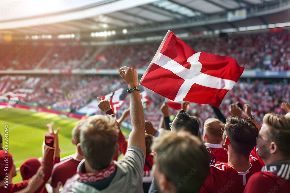 Fototapeta premium Fans waving the flag of Denmark at a football match, with the stadium crowd in the background