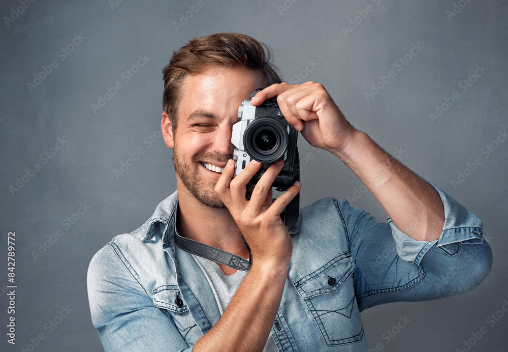 Lens, photography and man with camera in studio for digital media, production and photoshoot. Happy, photographer and smile with dslr equipment for journalist, picture and art and on grey background Lens, photography and man with camera in studio for digital media, production and photoshoot. Happy, photographer and smile with dslr equipment for journalist, picture and art and on grey background