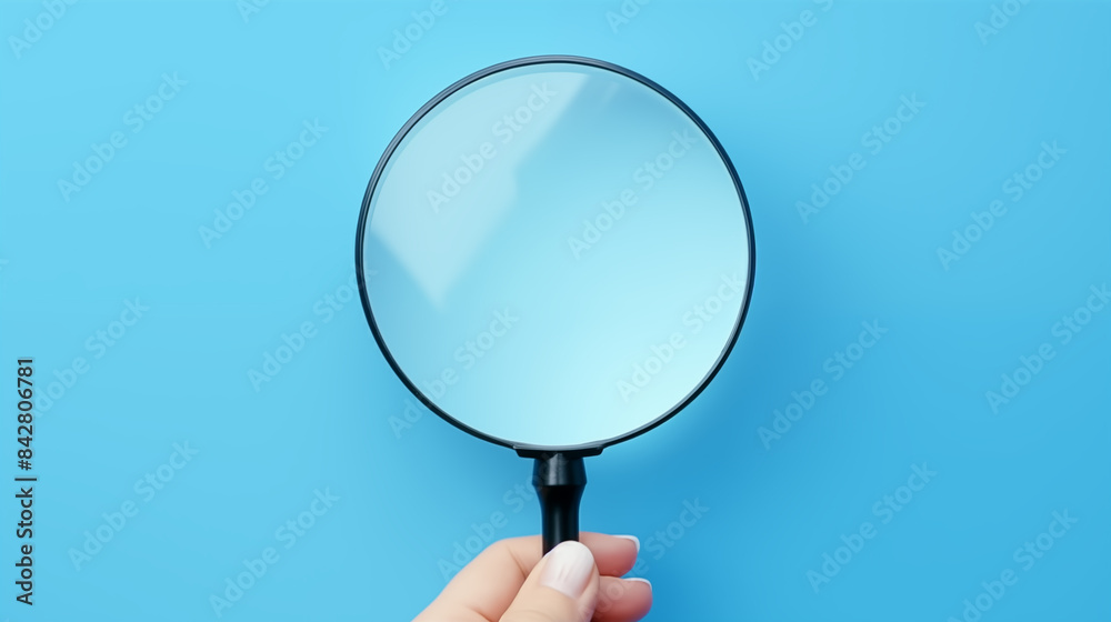Hand holding a magnifying glass on a blue background Hand holding a magnifying glass on a blue background