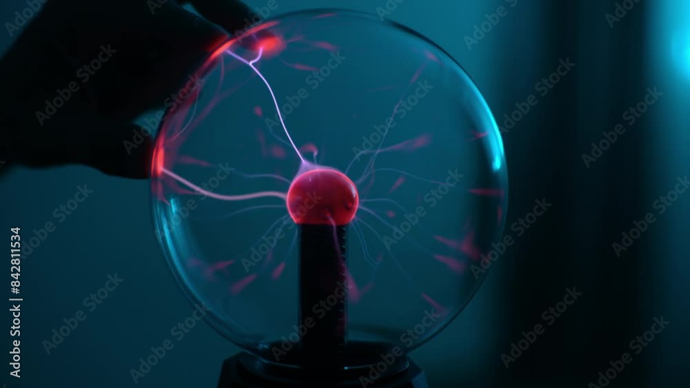 Close-up palm of unrecognizable man touching electric plasma ball with luminous flames during physical experiment. Closeup of plasma ball with many energy rays inside. Shooting in slow motion.
