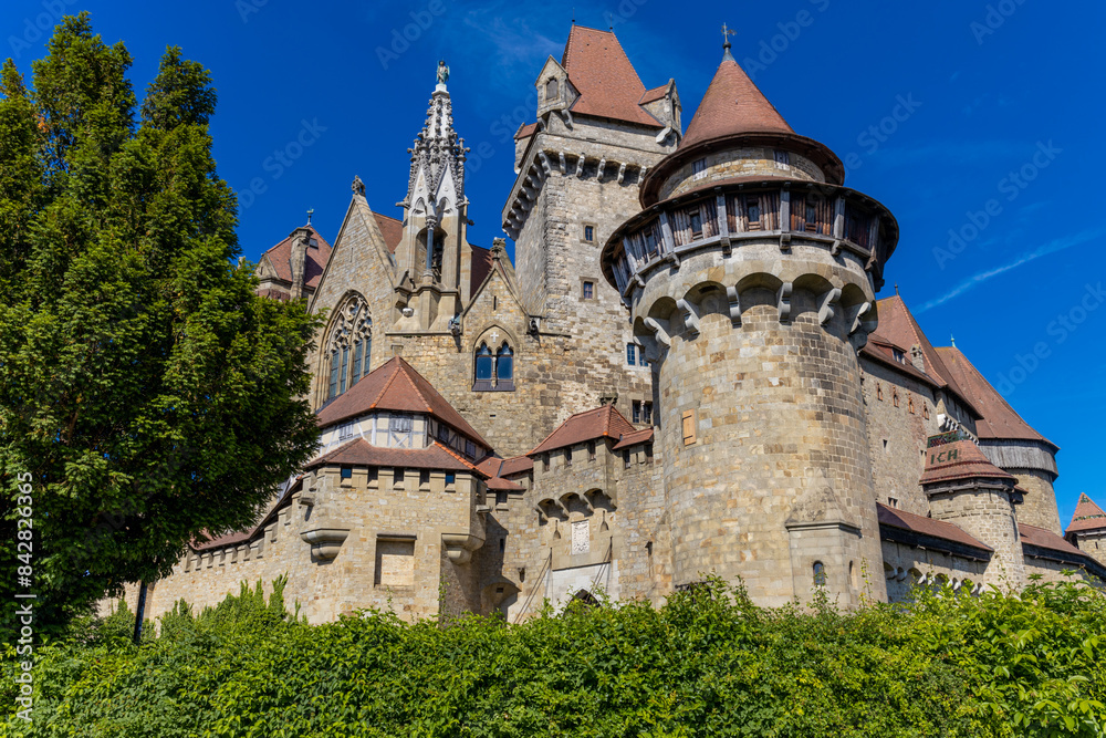 Castle landmark under blue sky. Medieval castle in Austria. Ancient historical sights around Vienna. Castle Kreuzenstein old building from outside Castle landmark under blue sky. Medieval castle in Austria. Ancient historical sights around Vienna. Castle Kreuzenstein old building from outside