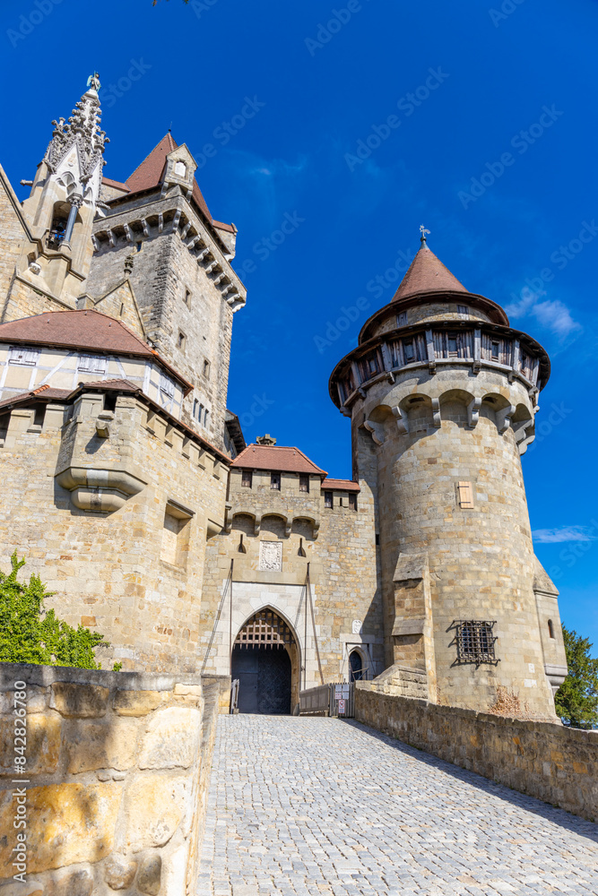 Castle landmark under blue sky. Medieval castle in Austria. Ancient historical sights around Vienna. Castle Kreuzenstein old building from outside Castle landmark under blue sky. Medieval castle in Austria. Ancient historical sights around Vienna. Castle Kreuzenstein old building from outside
