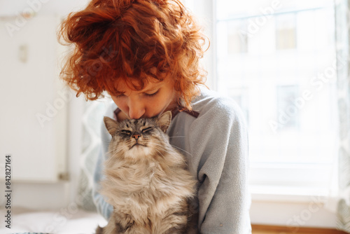 Portrait red-haired curly young woman with beloved fluffy domestic cat