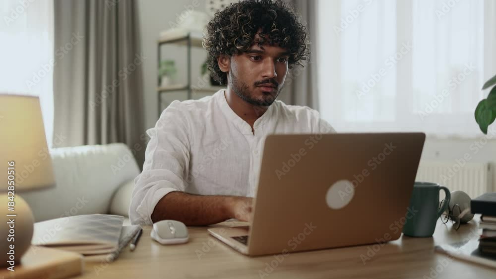 Handsome freelancer working on laptop checking email surfing web indoors Concentrated young indian man student has online distance education on computer and looking at screen at home workplace Handsome freelancer working on laptop checking email surfing web indoors Concentrated young indian man student has online distance education on computer and looking at screen at home workplace
