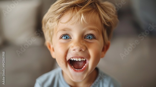 A delighted young boy with a beaming smile and shining blue eyes looking at the camera