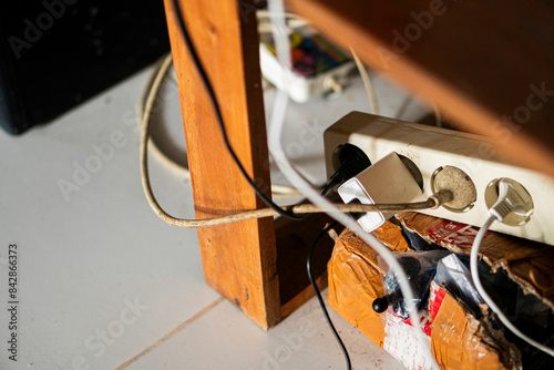 Cluttered power strip with tangled cables under a table