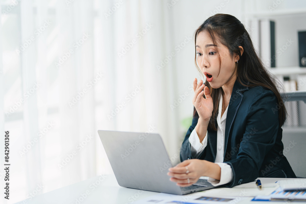 Businesswoman is sitting at a desk with a laptop open in front of her Businesswoman is sitting at a desk with a laptop open in front of her