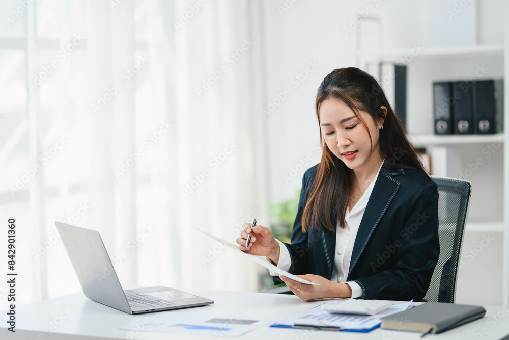 Business woman in a business suit is sitting at a desk with a laptop Business woman in a business suit is sitting at a desk with a laptop