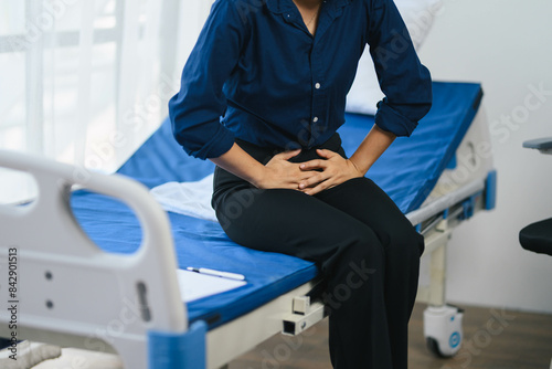 A woman is sitting on a hospital bed with a blue sheet