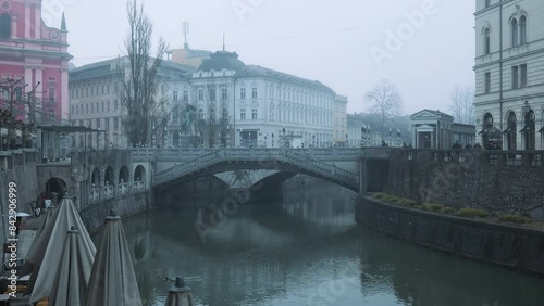Thick fog envelops Ljubljana, creating a mysterious view of the bridge over the Ljubljana River in slow motion.