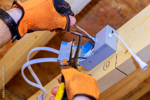 In new home construction, an electrician installs power junction box for LED recessed ceiling lights